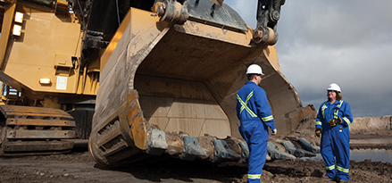 2 engineers in blue standing in front of shovel