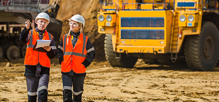 2 engineers in orange vests in front of mining truck