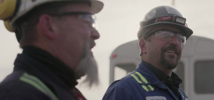 2 engineers wearing safety goggles smiling