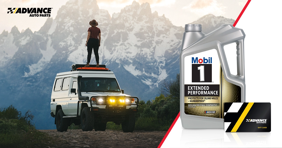 Woman stands on top of a white off-road SUV, looking towards a mountain range off in the distant background. A Mobil 1 motor oil bottle & Advance Auto Parts gift card displayed in the foreground.