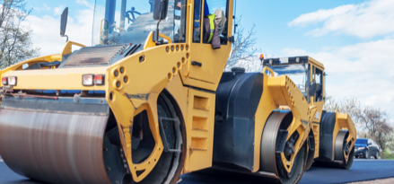 Two bulldozers paving the road 