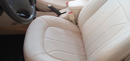 Repaired beige leather car seat and black steering wheel