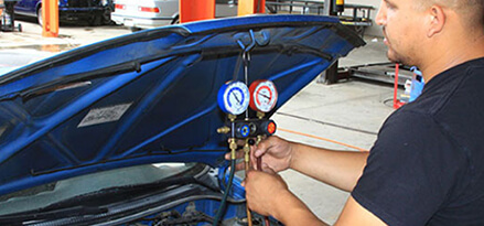 Mechanic works on car air conditioning and climate control