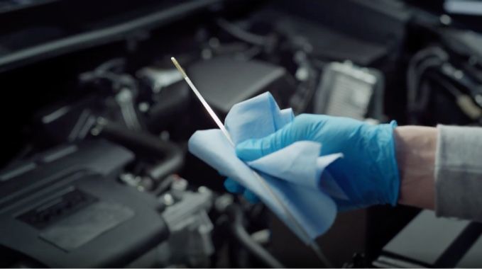 An image of someone checking the oil level on the dipstick of a vehicle.