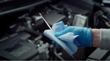 An image of someone checking the oil level on the dipstick of a vehicle.