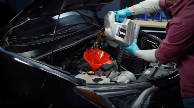 An image of someone pouring new oil into a vehicle.