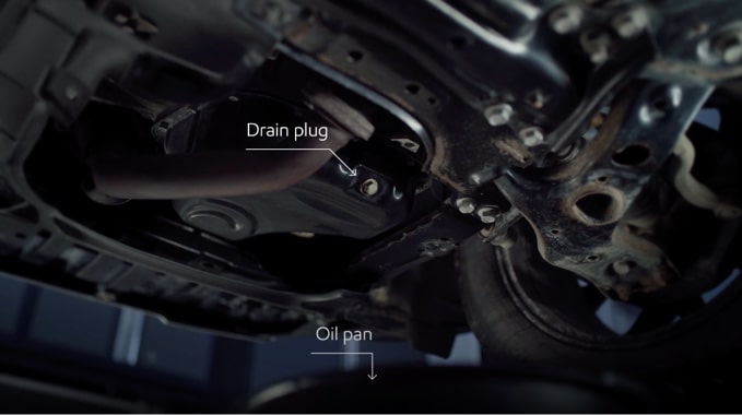 An image showing the drain plug and oil pan on a vehicle.
