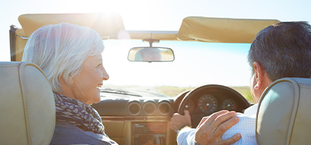 Mature couple driving with the top down.