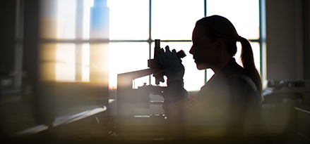 A woman looking into a microscope in a lab