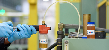 Mobil engineer collecting a lubricant sample from machinery as part of the lubricant testing process