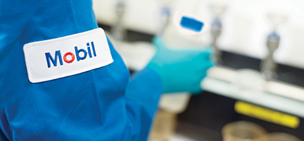Mobil technician holding a bottle with the Mobil logo on his arm