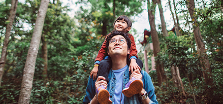Father carrying his child through a forest