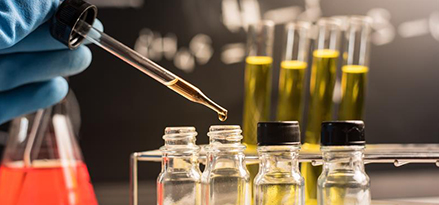 Technician using a pipette to transfer oil into a sample bottle