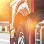 Sun flare shining on lower part of truck cab driving on highway 