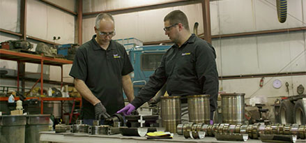 two technicians working with engine pieces spread on a table