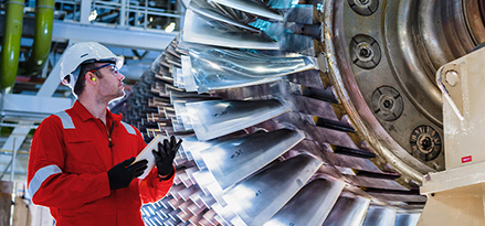 2 engineers in white hard hats inspecting turbine