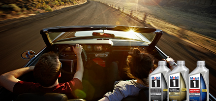 Couple in convertible car driving along scenic road.