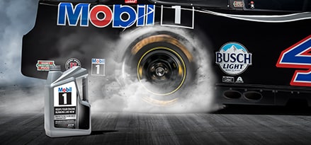 5 qts. of Mobil 1 motor oil with a race car doing a burnout in the background.