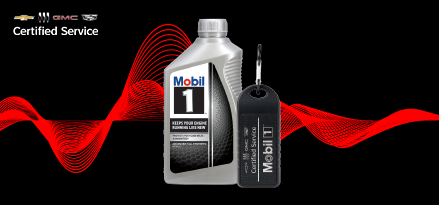 A bottle of Mobil 1™ motor oil and a black Bluetooth® speaker are locked up over a black background with red design elements behind them