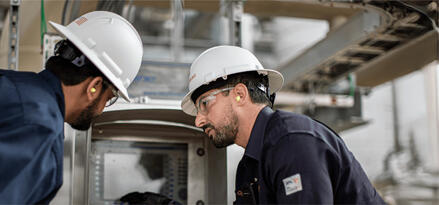Industrial workers inspecting equipment in a manufacturing facility.