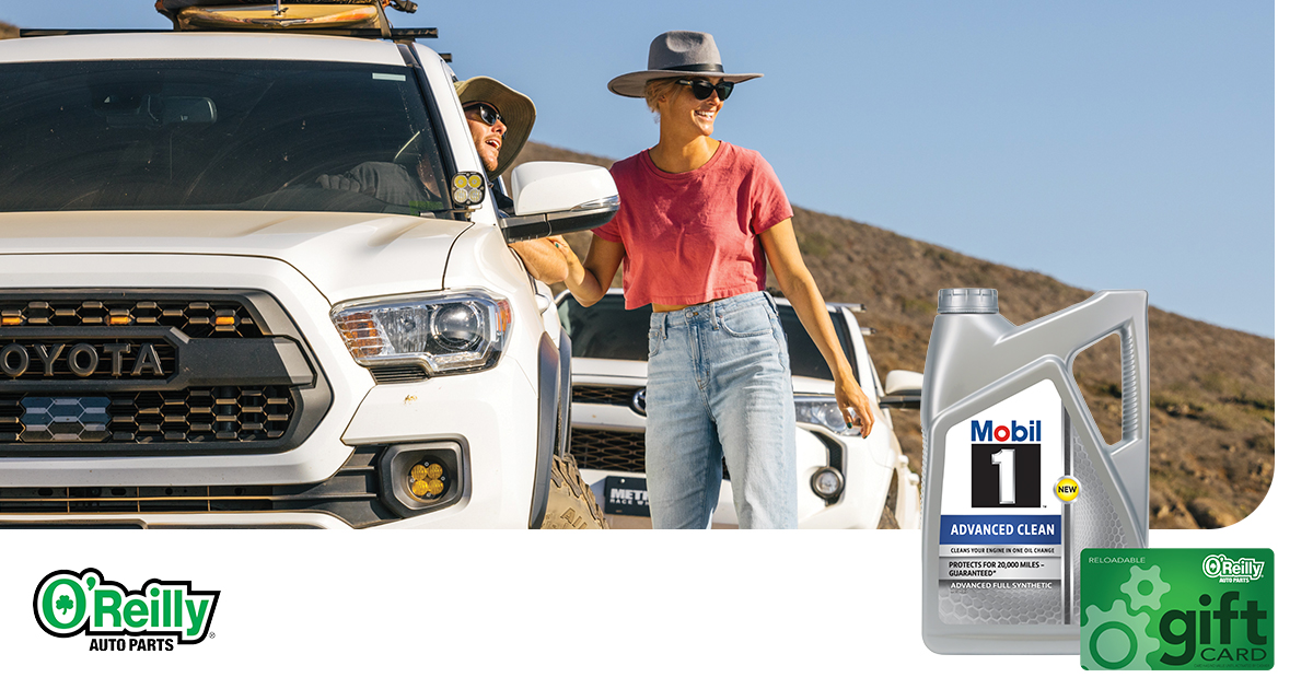 A woman, wearing a wide-brimmed hat, is seen standing near a white truck, talking to a man inside the car.