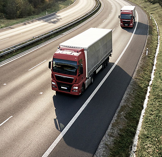 Red and white trucks driving down road